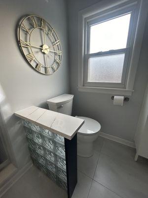 Custom glass block partial wall with quartz topper to separate toilet area