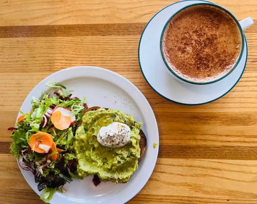 Smashed avocado toast on sourdough, dressed greens, and a dirty chai latte.