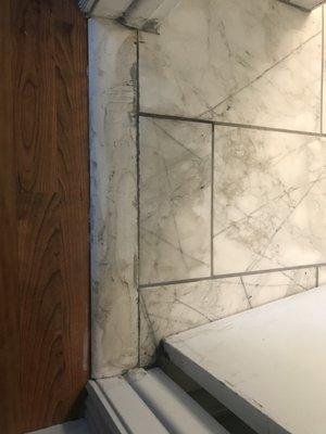 Poor tile cuts and chipped grout at doorway