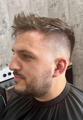 Messy textured hair with a mid skin fade on the sides