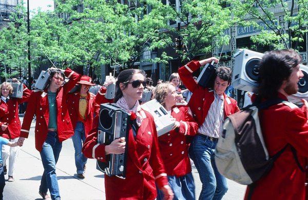 Marchers bumping hips together, on Boom Box Parade on State Street.  See marcher holding child's hand. Photo by Tom Brody.