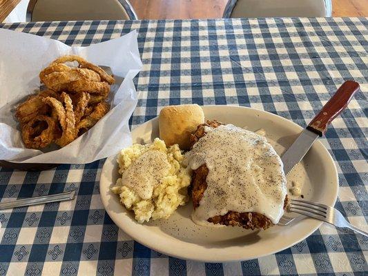 Chicken fried steak, mash potatoes, and onion rings.