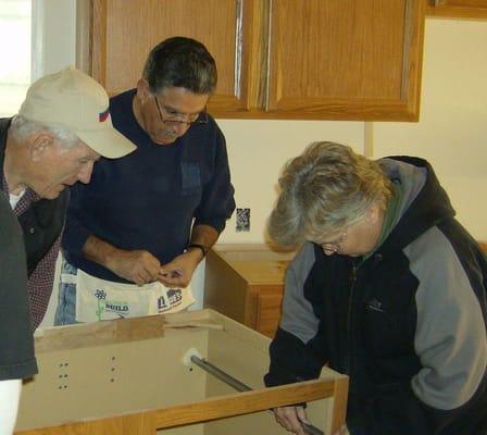 Diane teaching staff how to install kitchen cabinets