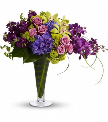 A lovely mix of blue hydrangea, green cymbidium orchids, mokara orchids, lavender roses and lots more are delivered in a footed vase.