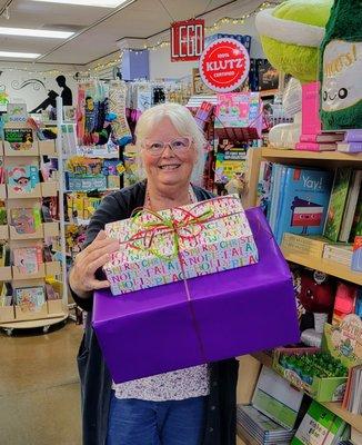 Lesa Smith, owner of Whiz Kids Toys holding wrapped gifts. We offer free gift wrapping on every purchase!