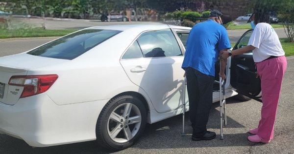 Senior with walker helped into sedan.