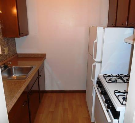 Galley style kitchen with new countertops and newer appliances including a gas range/stove