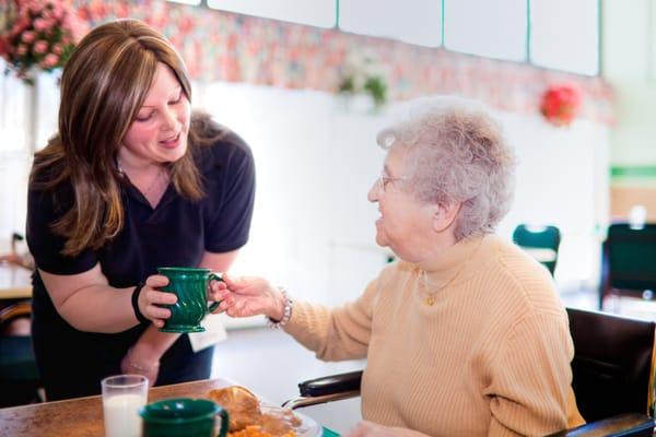 A staff member brings a beverage to a resident.