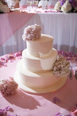 Lovely petals laid down on cake table with flowers placed on the wedding cake