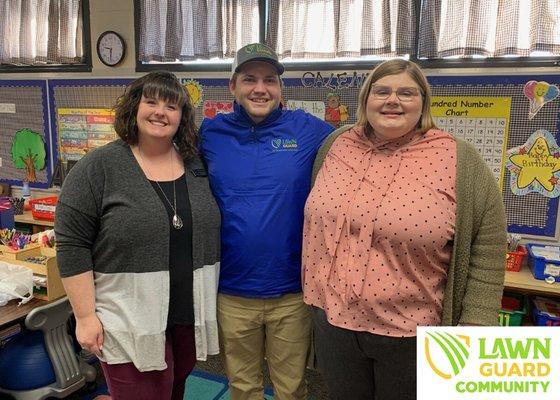 Lawn Guard Team members John Titus and Elaina Wiltshire with Mrs. Tucker of Pratt Elementary for Lawn Guard Community.