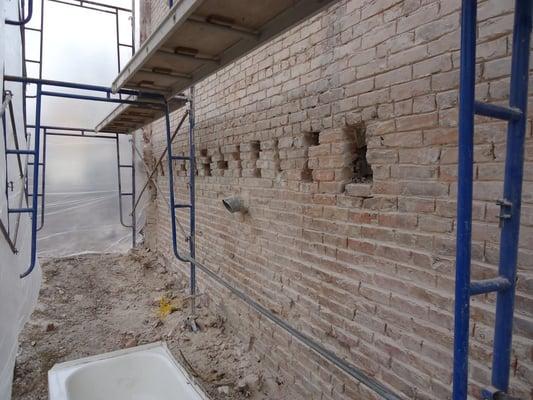 Tuck pointing brick walls. repair and replace missing bricks.