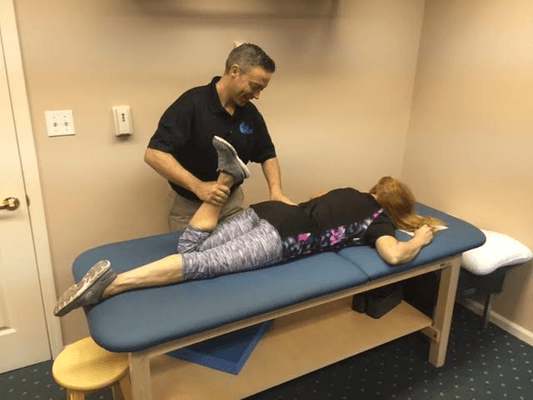 Dr. Jeff stretching one of our patients before she goes through her exercises.