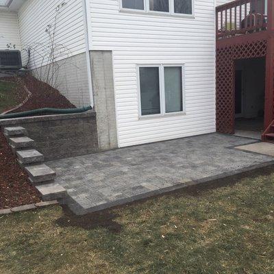 Paver patio with stone retaining wall and mulch beds blocked off by edging in Bennet, NE.