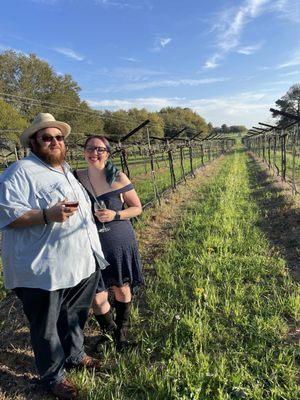 My husband and I between the vines outside. Definitely want to come back here when there are grapes on the vines!