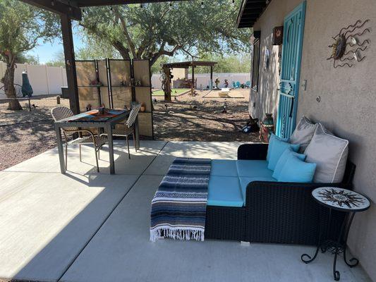 Covered patio of the tiny home with day bed and dining table.