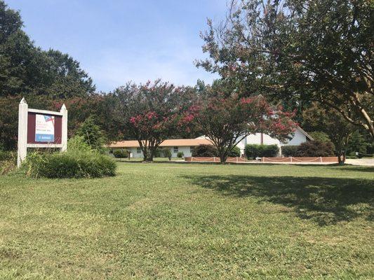 Front view.  Beautiful Crape Myrtles on a semi-circular drive through.  The parking lot is to the right of the building.