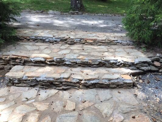 Incomplete flagstone installation with loose rocks, cracking mortar, and uneven stones.