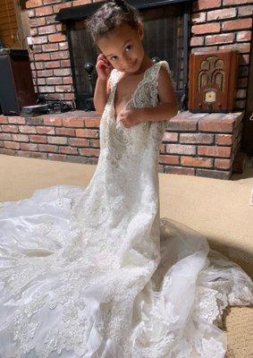 Beautiful little girl showing off her mom's wedding dress.