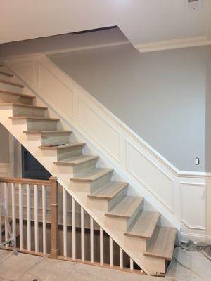 A stain  and paint staircase install chair railing on walls and make the little squares