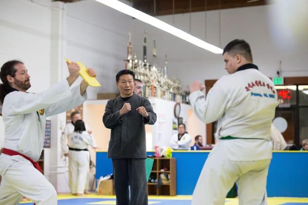 Great Grand Master Lee giving positive encouragement to a student practicing their board-breaking technique.