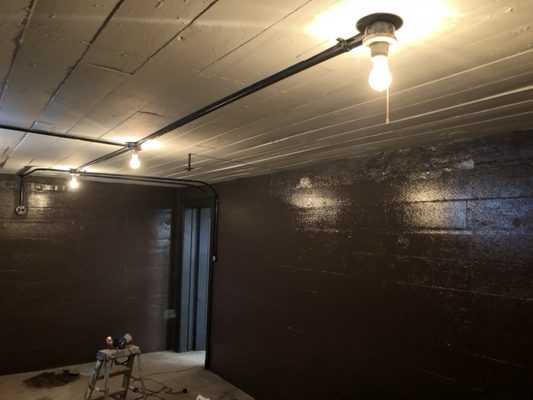 Painted block walls and concrete ceiling and lighting electrical conduit in basement wine cellar