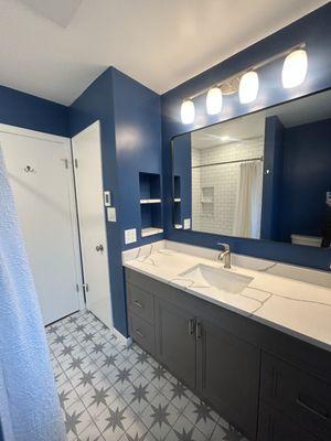 Striking blue paint, star pattern tiles and veined quartz counters completely update this 50's Chicago ranch bathroom