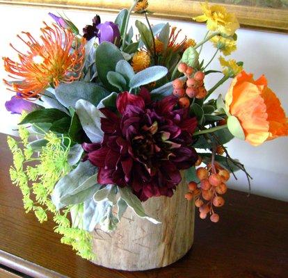 Colorful mix of flowers in a tree branch vase.