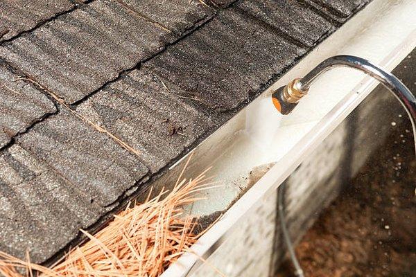 Power washing gutters for a thorough cleaning.