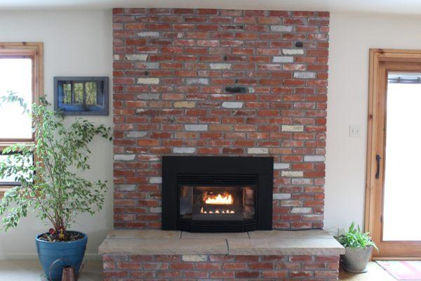 Fireplace rebuilt using reclaimed common brick and a sandstone hearth. Classic country style.