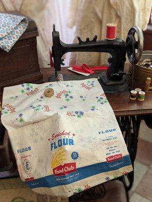 Flour sack being made into a pillow case.  (My mother's sewing machine was like that one too... a treadle to power the machine)