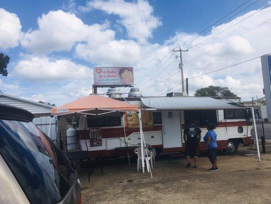 Food truck is in between a gas station and the laundry mat.