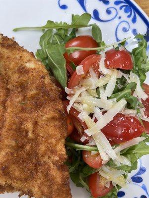 Pollo alla milanese,  Chicken Milanese with arugula, Cherry tomatoes and shaved Parmigiano reggiano, dressing of extra virgin olive oil.