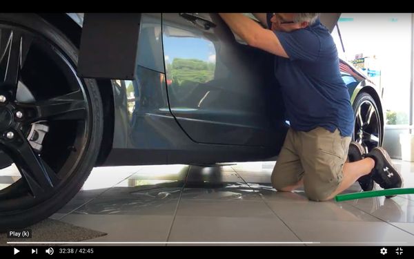 Paintless dent repair being performed on a showroom Camaro