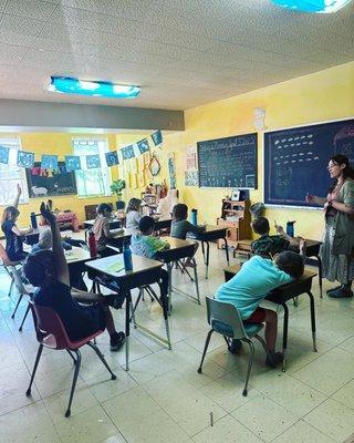 In this cozy yellow classroom, children actively engage in the process of learning, guided by a dedicated teacher.