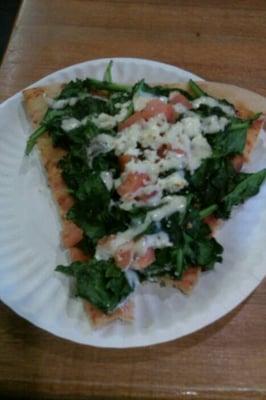 Spinach pizza with tomatoes, garlic, feta cheese, diced tomatoes, & ranch (buttermilk I think) dressing.