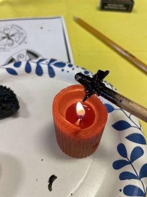 Using a candle to heat the tool and melt the beeswax for drawing.