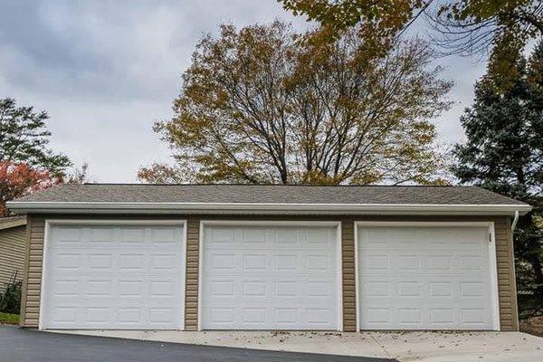 3 car garage with shingle roof and vinyl siding