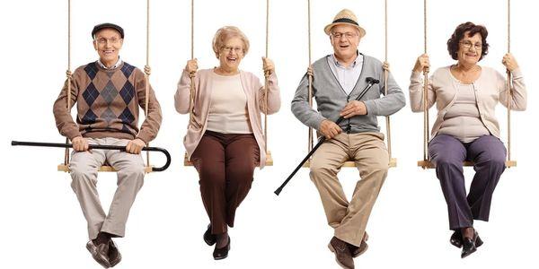 four seniors sitting on swings smiling and laughing