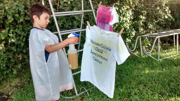 Concentrating on his work - painting on t shirts