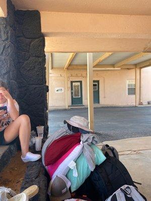 My kid waiting next to all our stuff and their crap little office door in the back ground.