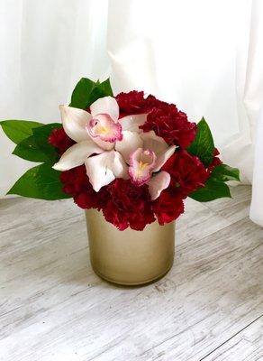 A luxurious arrangement of dark red carnations and white cymbidium orchids.