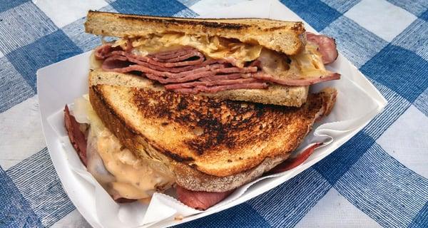 Corned Beef Reuben- tall stack of house corned beef, swiss cheese, sauerkraut, thousand island, grilled on toasted rye