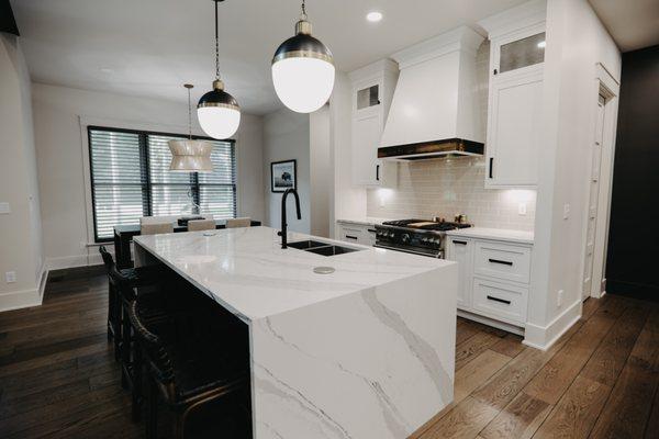 This open concept kitchen has Weber Dutch custom cabinetry, a Cambria Quartz countertop, color is Brittanica with a waterfall edge.