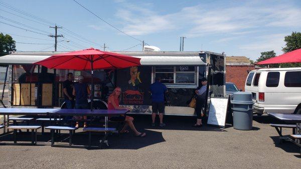 The food truck is in the parking lot of the market