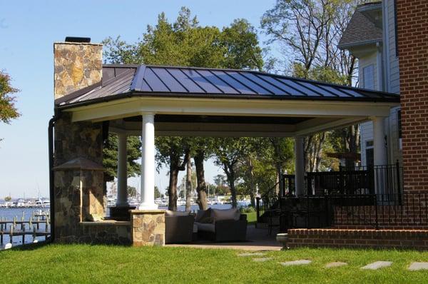 Outdoor living area with masonry chimney, bar, kitchen area, with Azek trim work and metal seem roof.