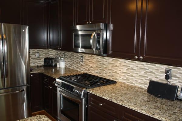 Kitchen renovation by Legendary Renovations featuring refinished, melamine cabinets, new granite, backsplash and paint.