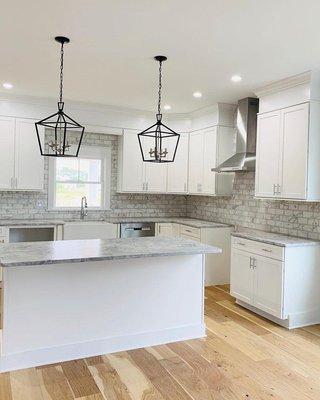 Farmhouse inspired marble kitchen with white cabinets.