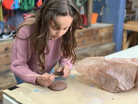 Outdoor workshop where students make projects with clay, wood, and cardboard.