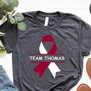 Could you give me a price on dark Heather gray tee shirts with burgundy and ivory ribbon with TEAM CHIP OR CHOPS TEAM.