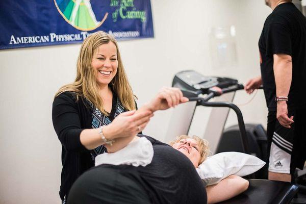 Occupational therapist assisting with shoulder exercise in Maple Grove clinic's gym.